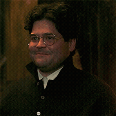 A Man Wearing Glasses And A Black Shirt Smiles For The Camera GIF