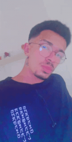 A Man Wearing Glasses And A Black Shirt With Chinese Writing GIF