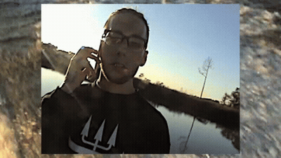 A Man Wearing Glasses And A Black Shirt With The Letter L On It GIF
