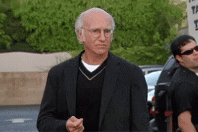 A Man Wearing Glasses And A Black Suit Is Standing In Front Of A Sign That Says ' The ' On It GIF