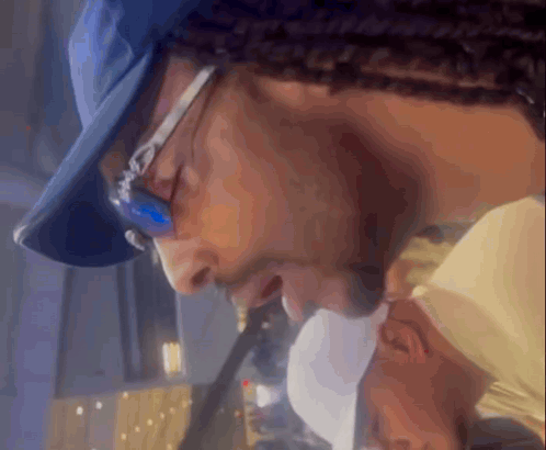 A Man Wearing Glasses And A Blue Hat Looks Down GIF