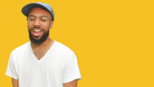 A Man Wearing Glasses And A Blue Hat Stands In Front Of A Yellow Background That Says Yes Lawd GIF