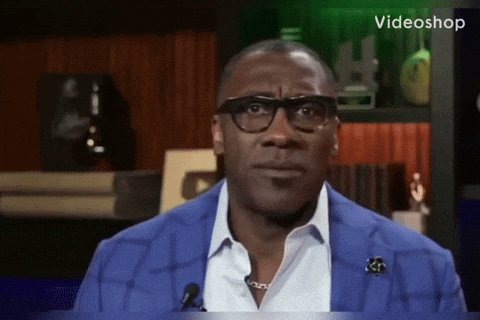 A Man Wearing Glasses And A Blue Jacket Is Sitting In Front Of A Microphone With The Word Videoshop On The Bottom GIF