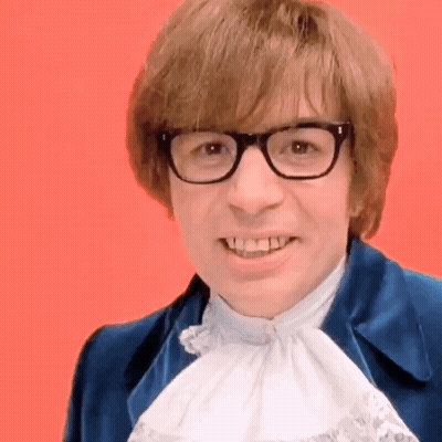 A Man Wearing Glasses And A Blue Jacket Smiles GIF