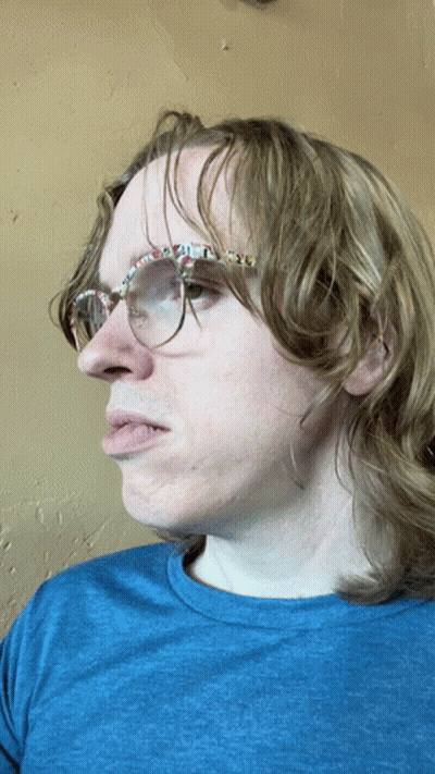 A Man Wearing Glasses And A Blue Shirt Is Making A Face GIF