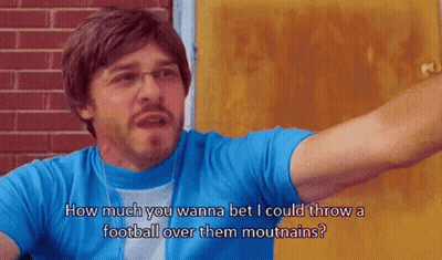 A Man Wearing Glasses And A Blue Shirt Says How Much You Wanna Bet I Could Throw A Football Over Them Mountains GIF
