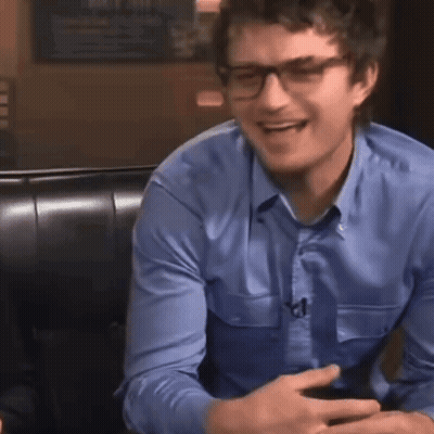 A Man Wearing Glasses And A Blue Shirt Smiles GIF