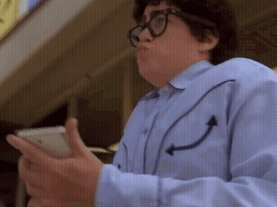 A Man Wearing Glasses And A Blue Shirt With Arrows On The Sleeves Is Holding A Cell Phone GIF