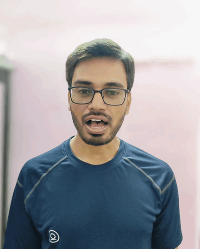 A Man Wearing Glasses And A Blue Shirt With The Letter A On It Makes A Funny Face GIF