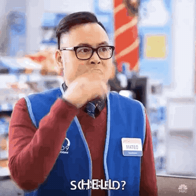 A Man Wearing Glasses And A Blue Vest Is Making A Funny Face And Saying Scheld ? GIF