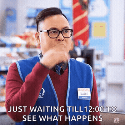 A Man Wearing Glasses And A Blue Vest Is Waiting To See What Happens GIF