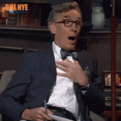 A Man Wearing Glasses And A Bow Tie Is Sitting On A Couch With His Mouth Open And The Words Bill Nye Behind Him GIF