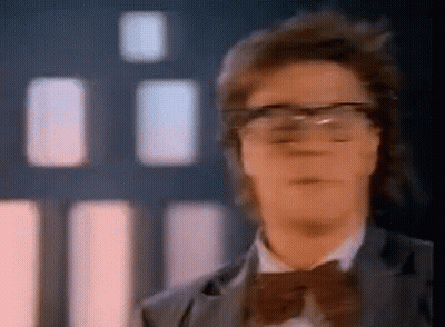A Man Wearing Glasses And A Bow Tie Looks At The Camera . GIF