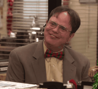 A Man Wearing Glasses And A Bow Tie Smiles At The Camera GIF