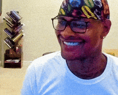 A Man Wearing Glasses And A Colorful Headband Smiles GIF