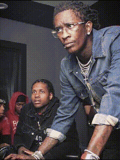 A Man Wearing Glasses And A Denim Jacket Is Standing In A Crowd GIF