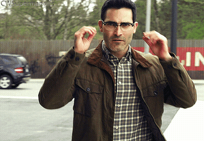 A Man Wearing Glasses And A Green Jacket Is Standing In Front Of A Sign That Says Cws Superman Gifs GIF