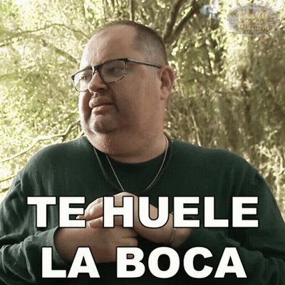 A Man Wearing Glasses And A Green Shirt Has The Words Te Huele La Boca On His Chest GIF