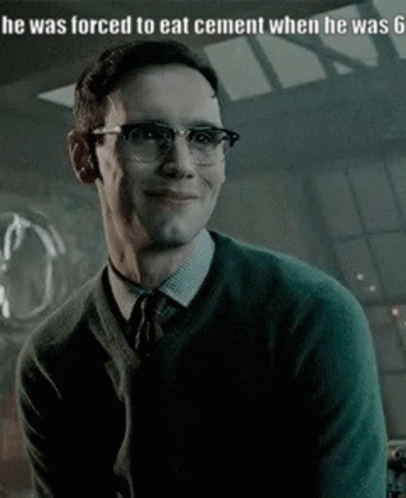 A Man Wearing Glasses And A Green Sweater Is Smiling And Looking At The Camera . GIF
