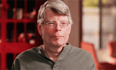 A Man Wearing Glasses And A Grey Shirt Is Looking At The Camera GIF