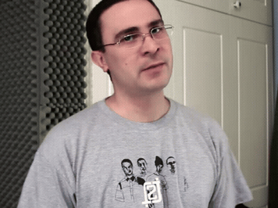 A Man Wearing Glasses And A Grey T-Shirt With A Picture Of A Group Of Men On It GIF