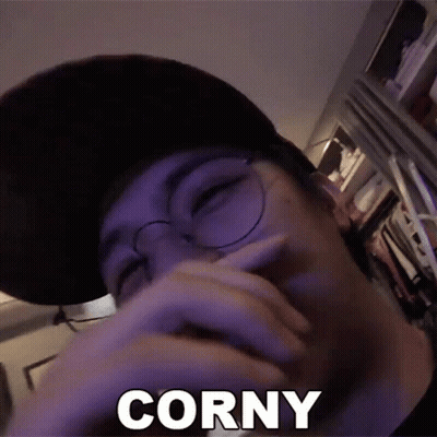 A Man Wearing Glasses And A Hat Is Covering His Mouth With His Hand And The Word Corny Is Visible . GIF