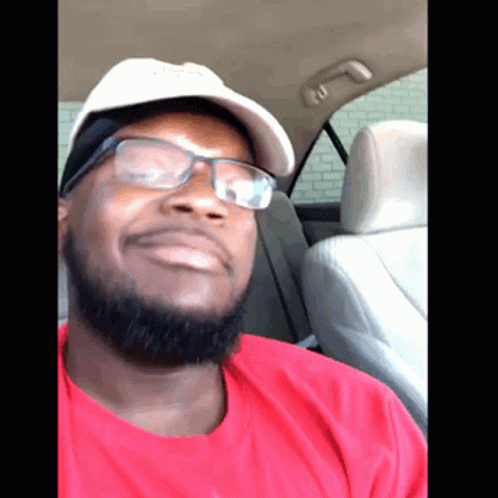 A Man Wearing Glasses And A Hat Is In A Car GIF