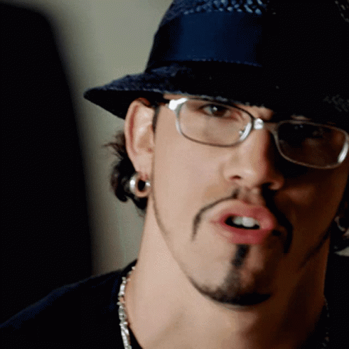 A Man Wearing Glasses And A Hat Is Making A Face GIF