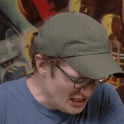 A Man Wearing Glasses And A Hat Is Making A Funny Face GIF
