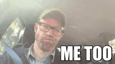 A Man Wearing Glasses And A Hat Is Sitting In The Back Seat Of A Car And Says Me Too GIF