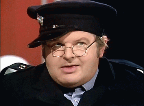 A Man Wearing Glasses And A Hat With A Badge That Says U.k. GIF