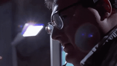 A Man Wearing Glasses And A Headset Is Looking Down GIF