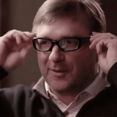 A Man Wearing Glasses And A Jacket Is Adjusting His Glasses . GIF