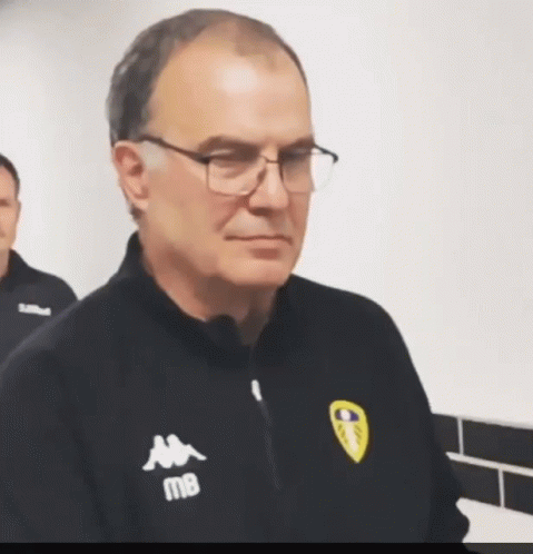 A Man Wearing Glasses And A Kappa Jacket Looks At The Camera GIF