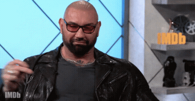 A Man Wearing Glasses And A Leather Jacket Is Standing In Front Of A Sign That Says Imdb On It GIF