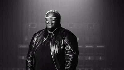 A Man Wearing Glasses And A Leather Jacket Smiles In A Black And White Photo GIF