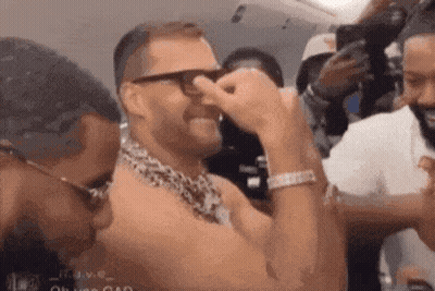A Man Wearing Glasses And A Leopard Print Scarf Is Covering His Nose . GIF