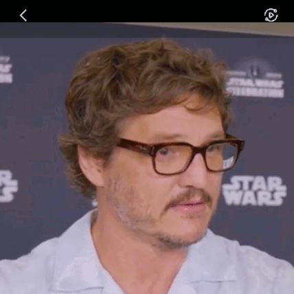 A Man Wearing Glasses And A Mustache Is Standing In Front Of A Star Wars Sign . GIF