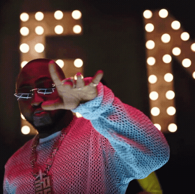 A Man Wearing Glasses And A Necklace That Says Fendi Is Making A Peace Sign GIF