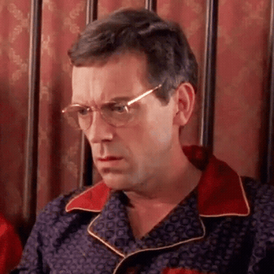 A Man Wearing Glasses And A Pajama Shirt Is Sitting In A Chair . GIF