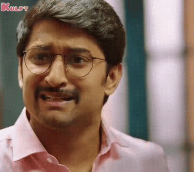 A Man Wearing Glasses And A Pink Shirt Making A Funny Face . GIF