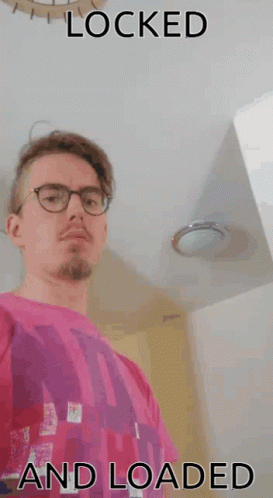 A Man Wearing Glasses And A Pink Shirt With The Words " Locked And Loaded " Below Him GIF