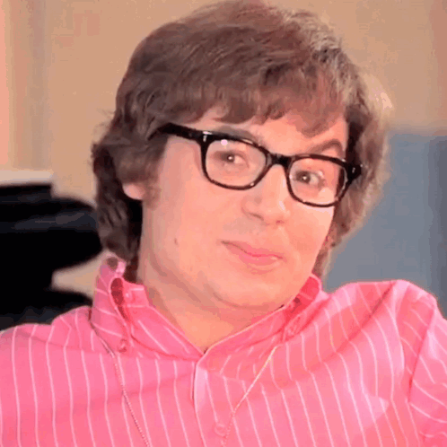 A Man Wearing Glasses And A Pink Striped Shirt Is Making A Funny Face GIF