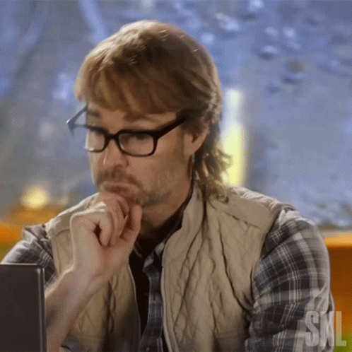 A Man Wearing Glasses And A Plaid Shirt Is Looking At A Computer Screen GIF