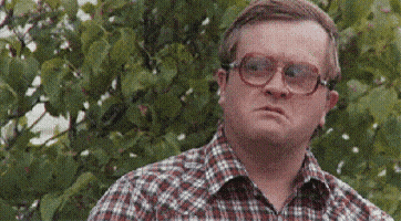 A Man Wearing Glasses And A Plaid Shirt Is Looking At Something . GIF