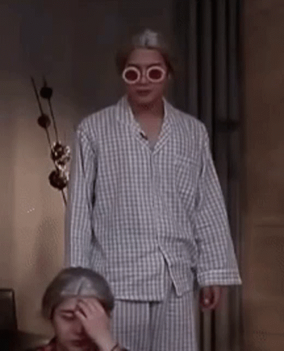 A Man Wearing Glasses And A Plaid Shirt Is Standing Next To A Woman Covering Her Face . GIF