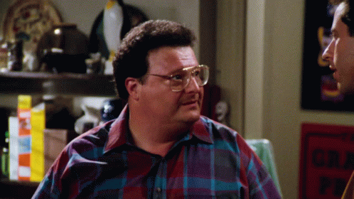 A Man Wearing Glasses And A Plaid Shirt Talks To Another Man In Front Of A Sign That Says No Parking GIF