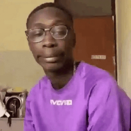 A Man Wearing Glasses And A Purple Shirt Is Making A Face . GIF