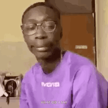A Man Wearing Glasses And A Purple Shirt Is Smiling . GIF
