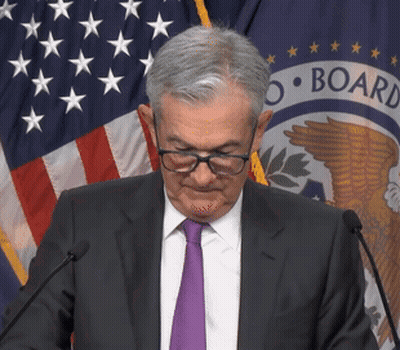 A Man Wearing Glasses And A Purple Tie Stands In Front Of A Microphone In Front Of A Flag That Says Board GIF